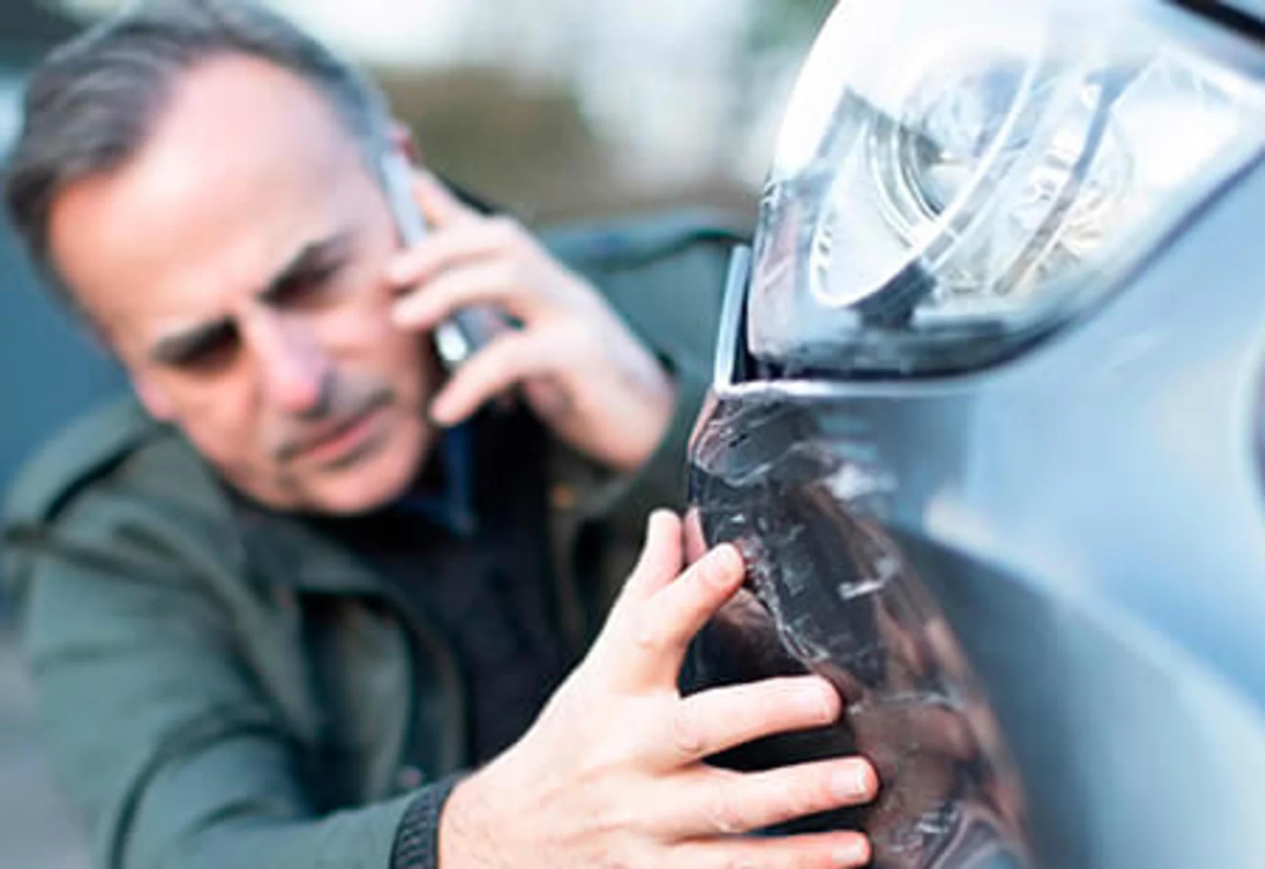 Mand kigger på sin bil, som har fået en skade