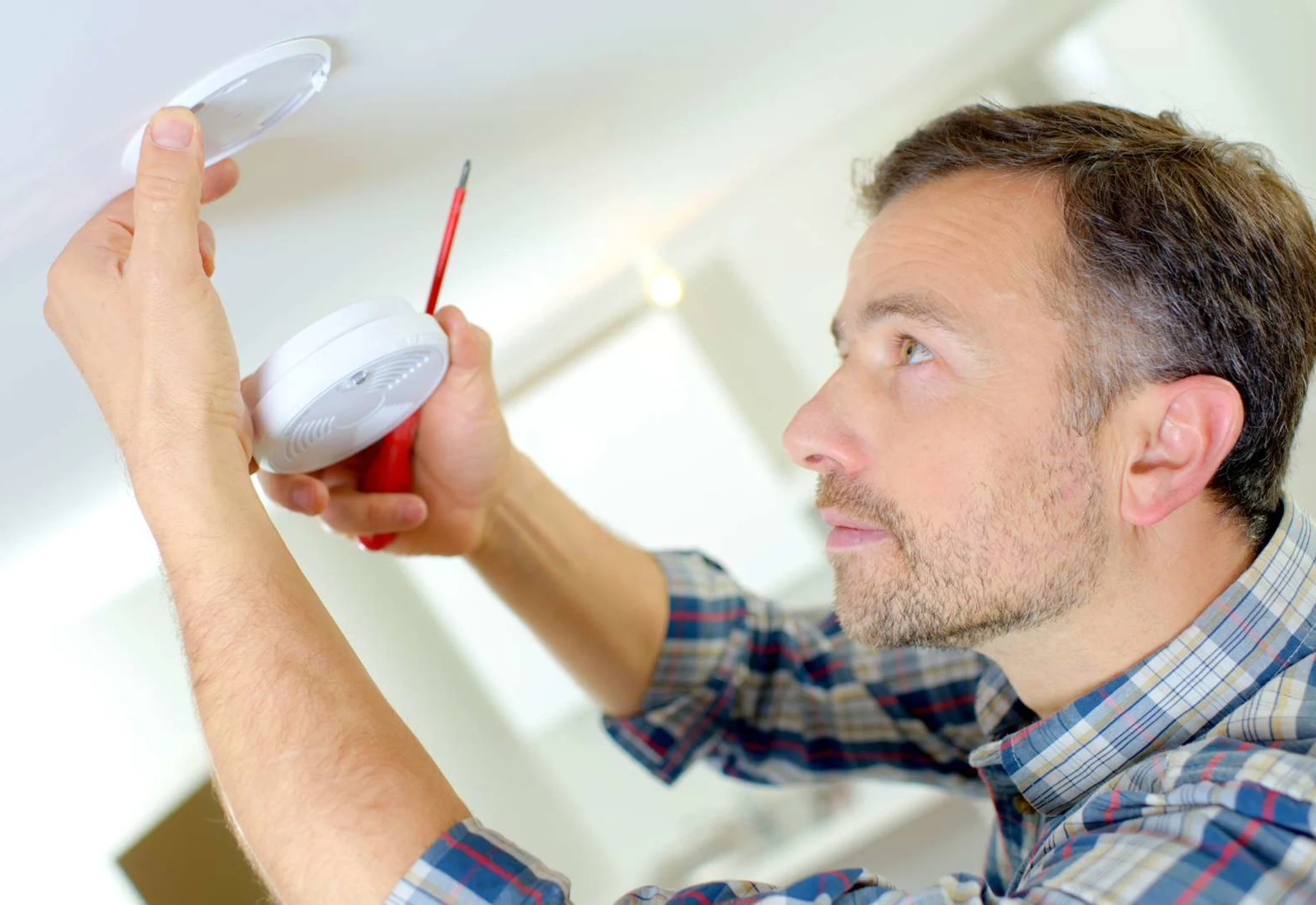 Mand som fikser sin brandalarm