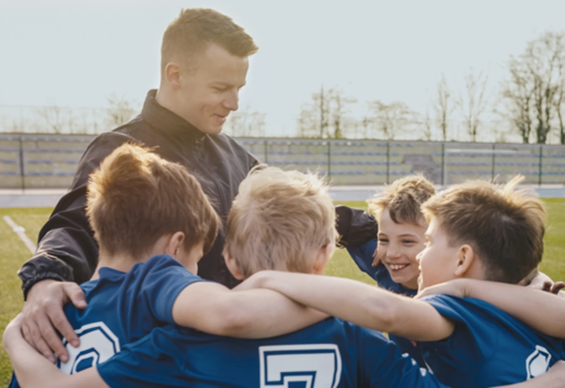 Drenge som som står i cirkel med en træner til fodboldkamp 