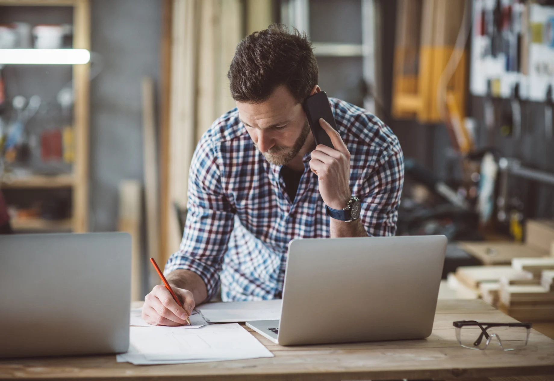 En håndværker som tegner og taler i telefon