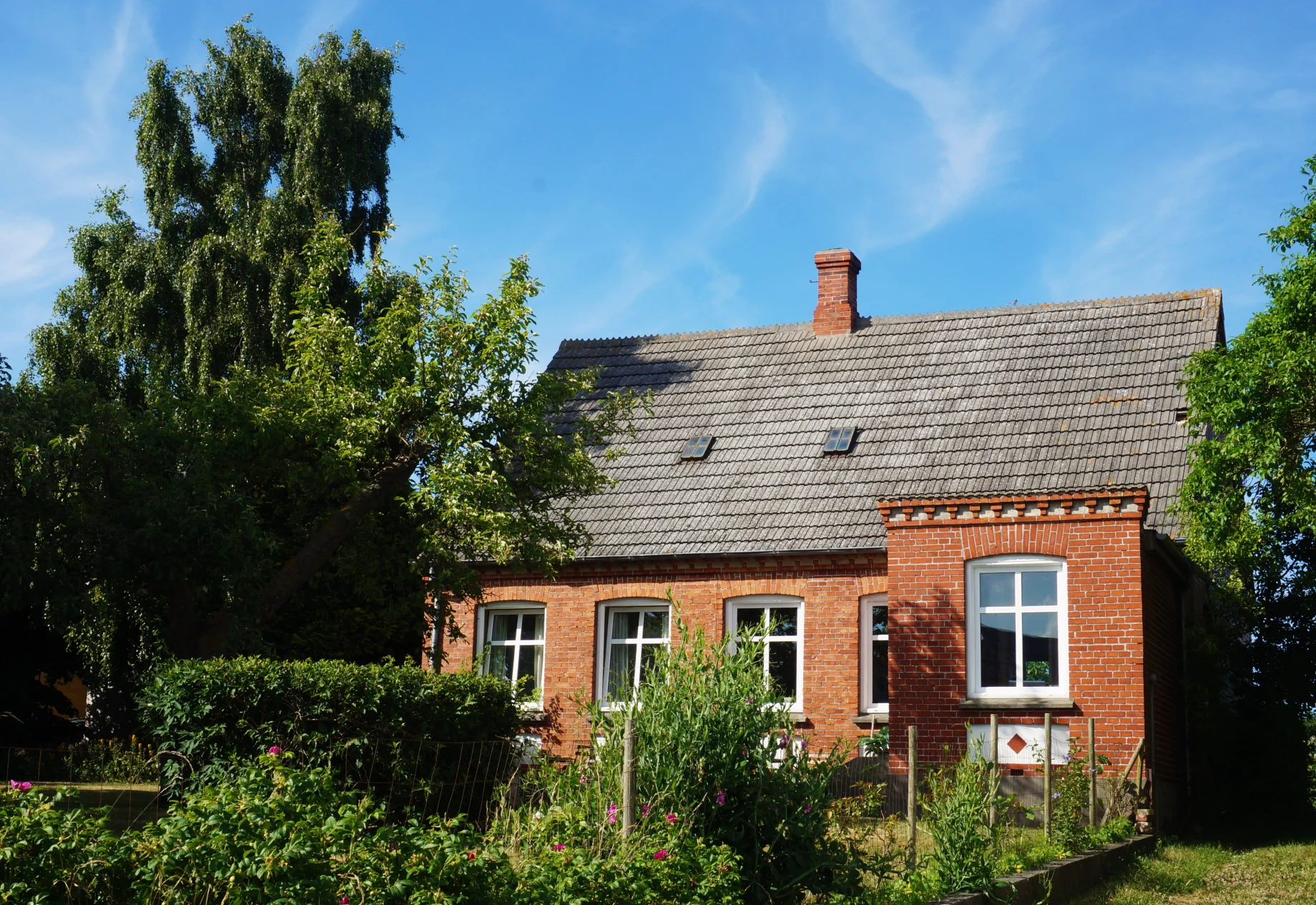 Et hus med blå himmel og træer omkring