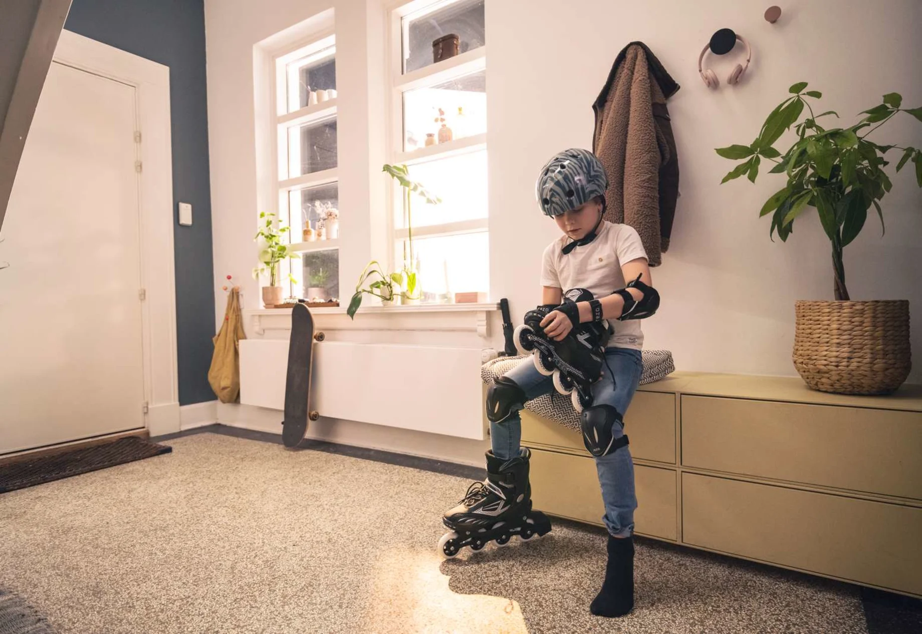Dreng med cykelhjelm, albuebeskyttere og rulleskøjter