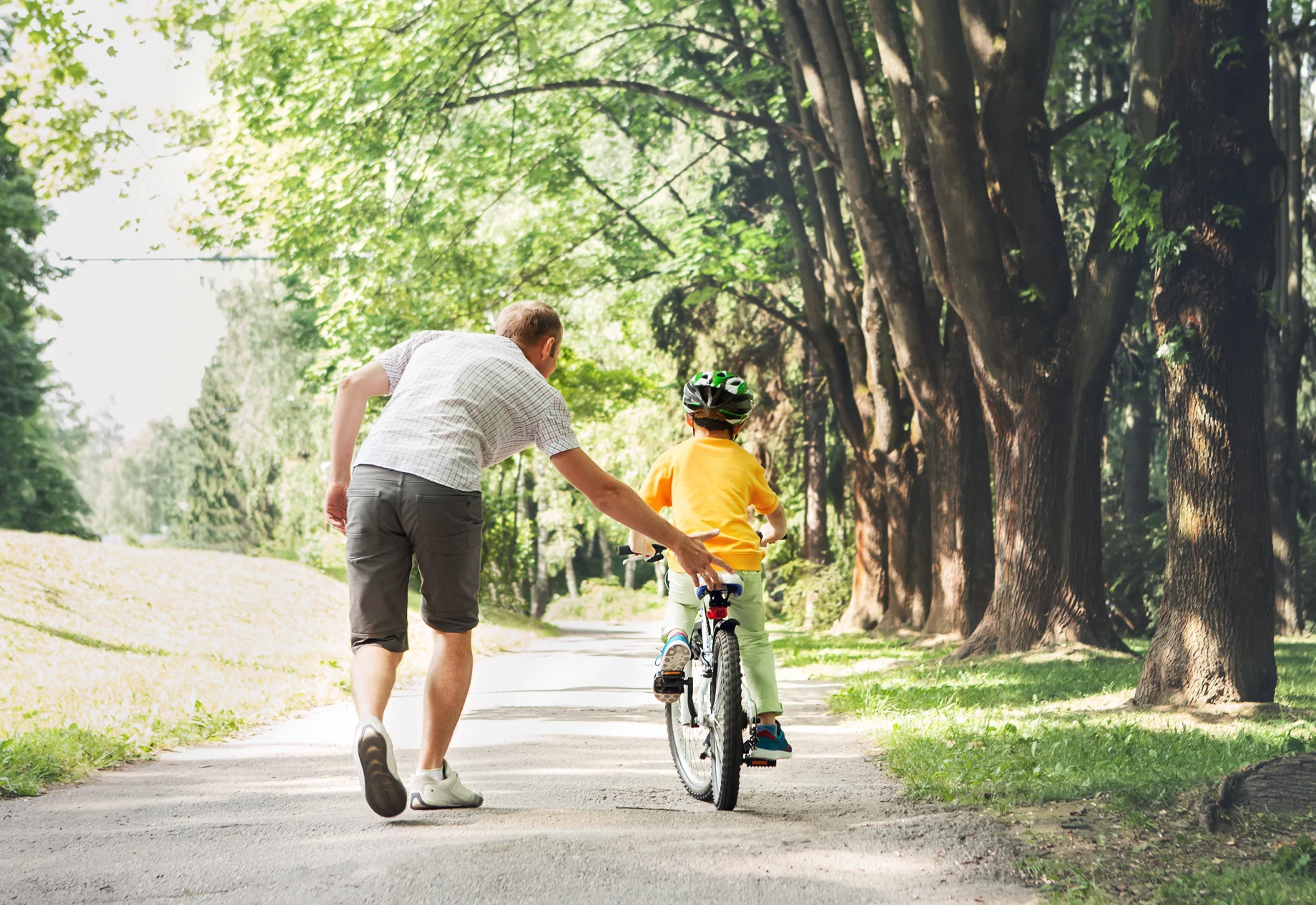 Mand som hjælper en lille dreng cykle i en skov