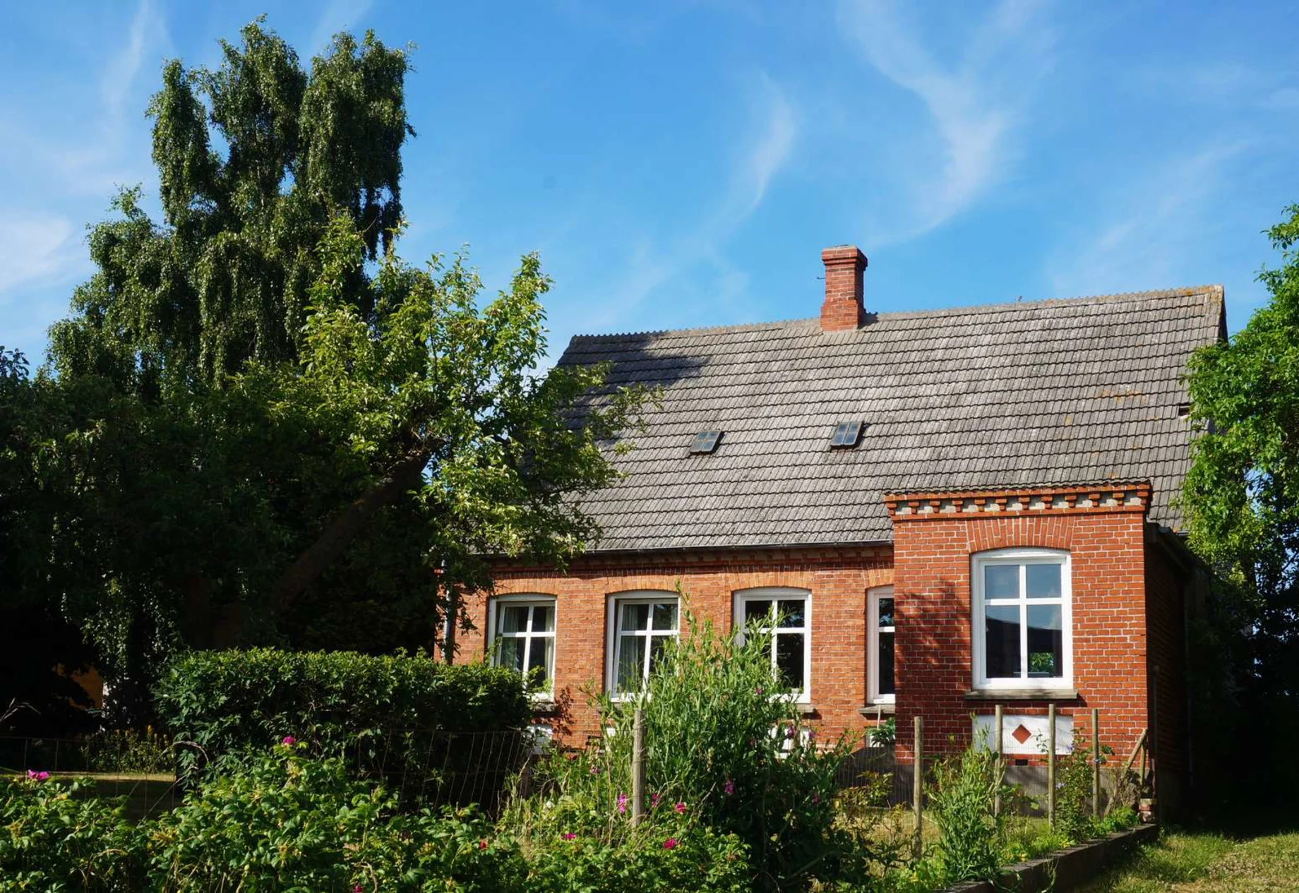 Hus med træer omkring og blå himmel