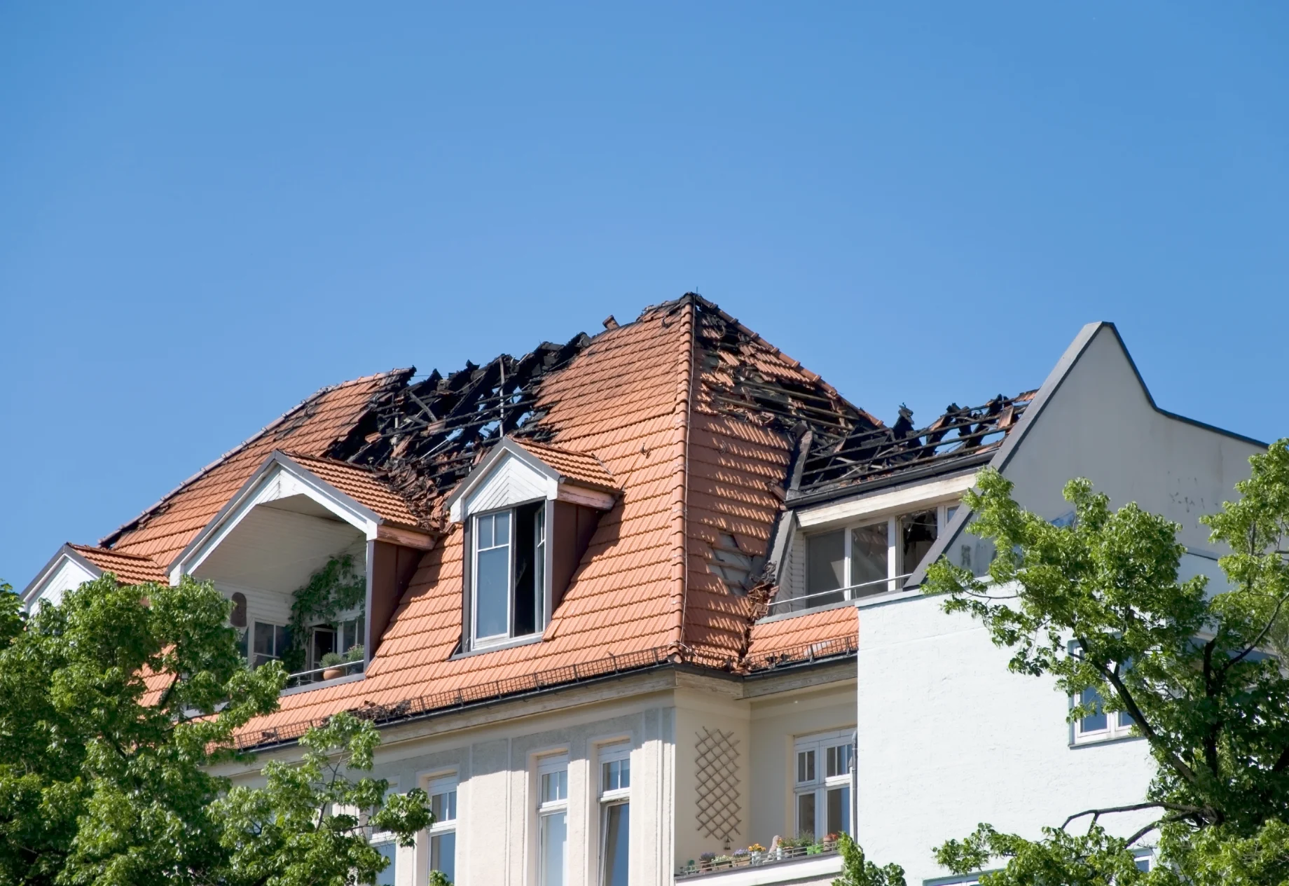 Et hvidt hus med brandskade i taget