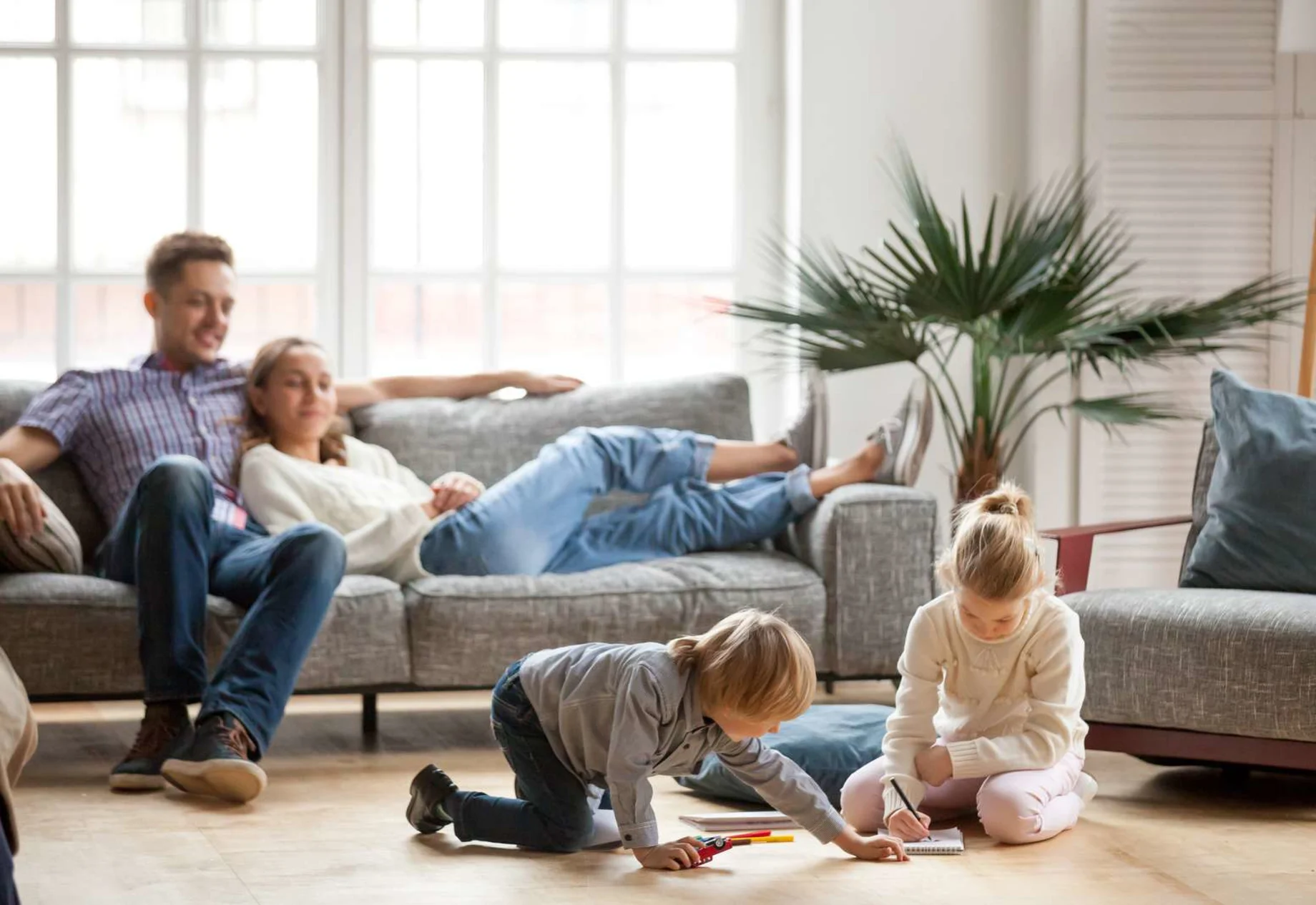 Forældre ligger i sofaen og børn leger på gulvet