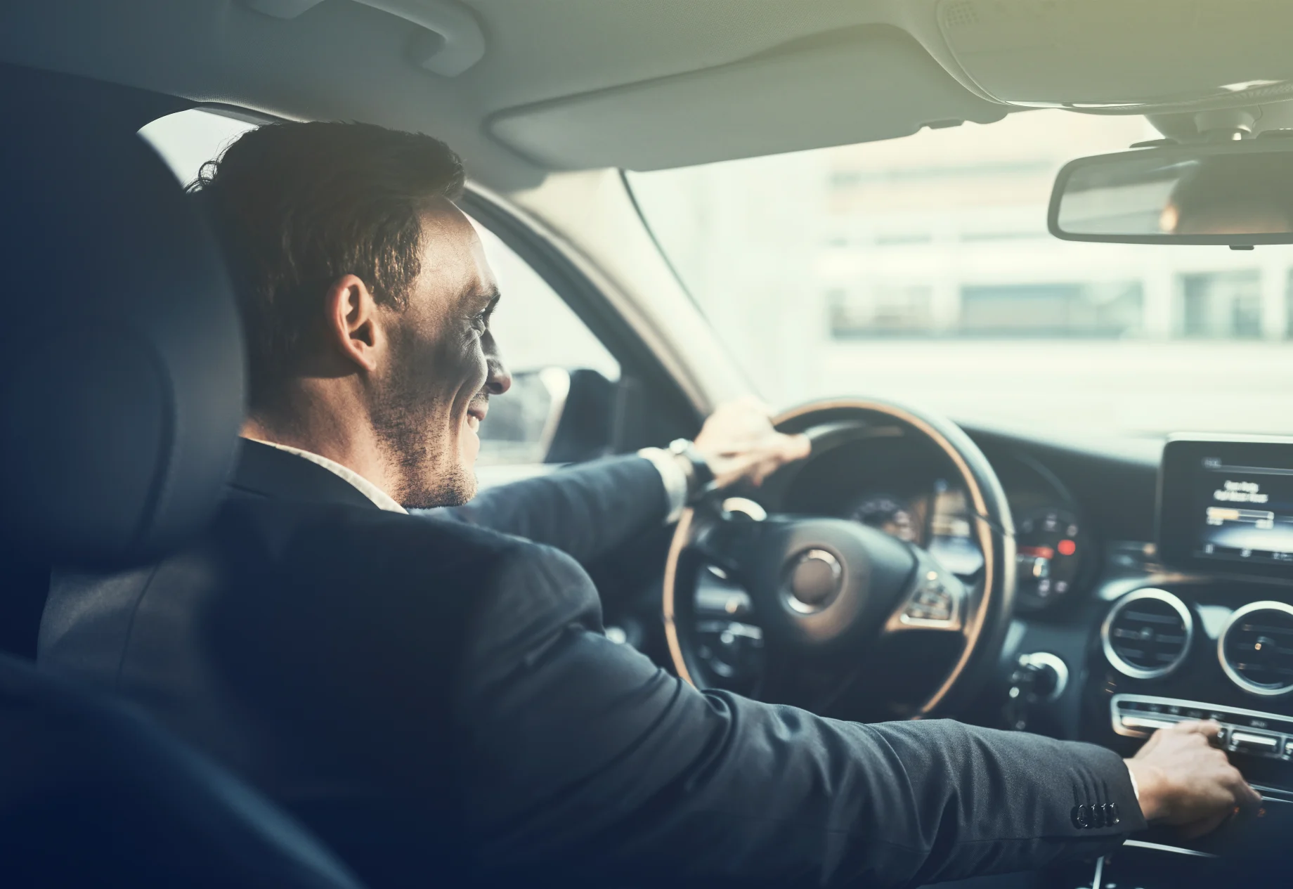 Mand i jakkesæt, som sidder inde i en bil