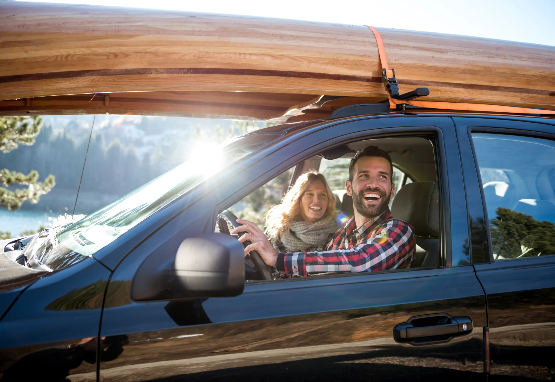 Mand og kvinde som sidder i bil. Ovenpå billedet er en kano