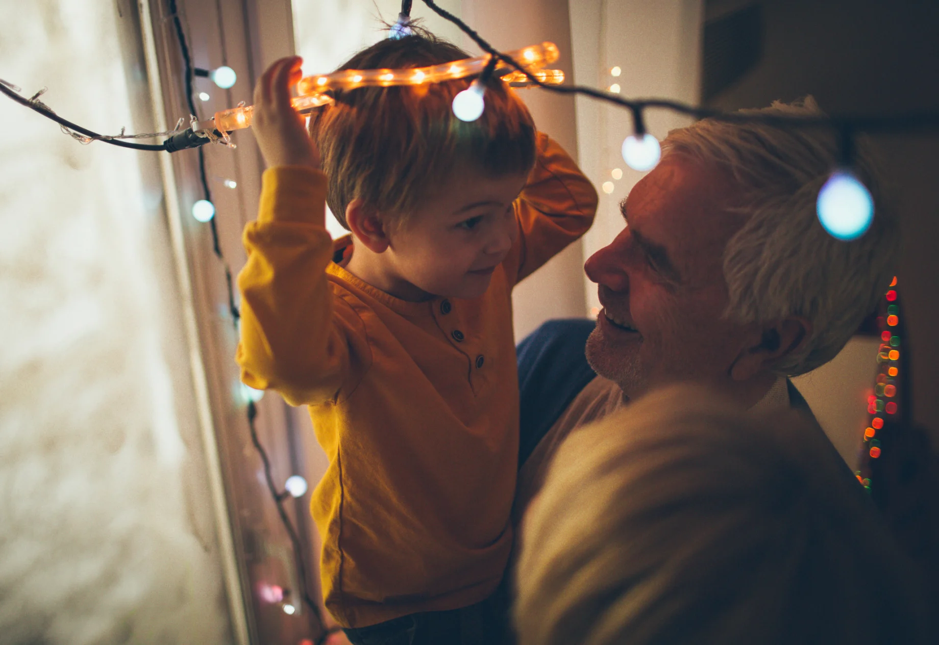 Barn og ældre person som står imellem en masse lyskæder