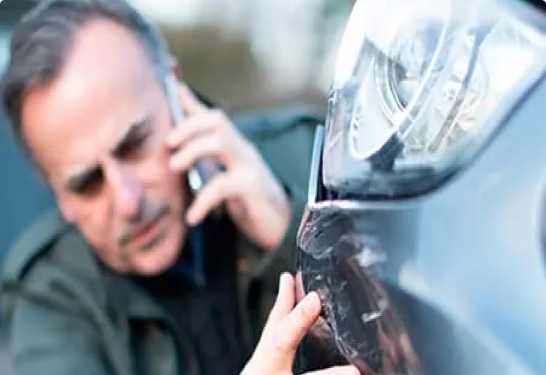 En mand som ringer til sit forsikringsselskab og har fået ridset sin bil