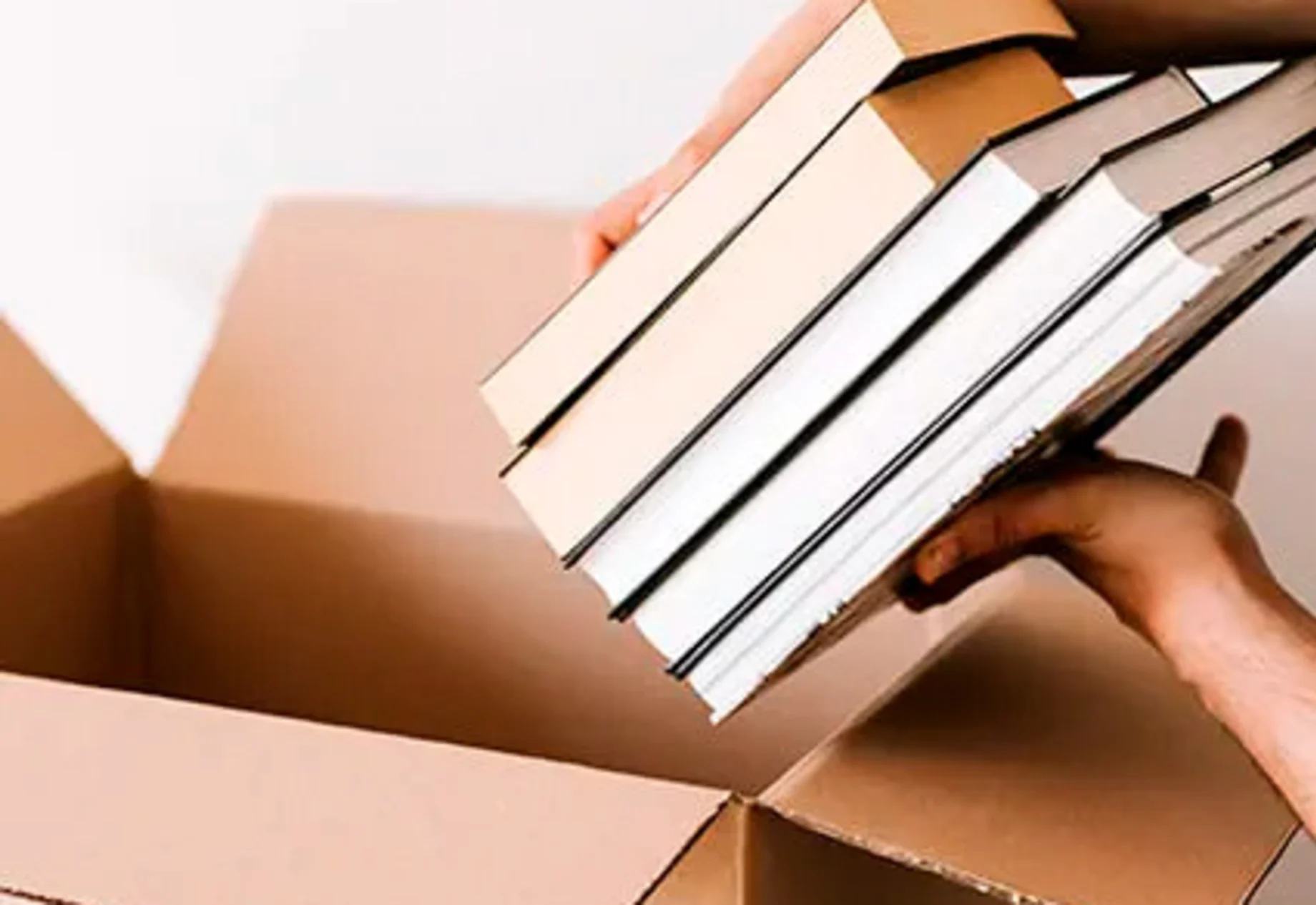 Bøger bliver pakket ned i en flyttekasse