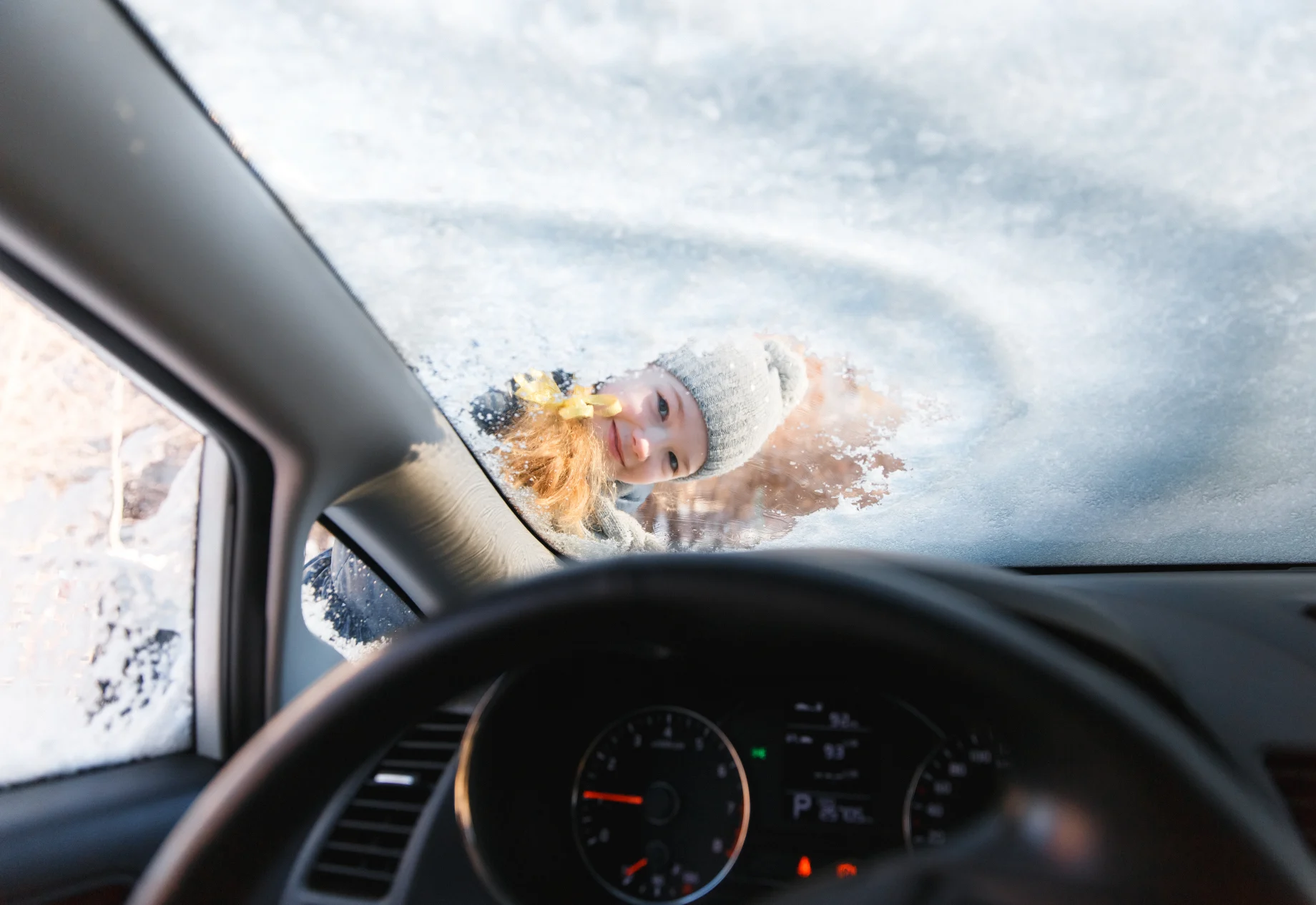 Pige, der fjerner sne fra forrude