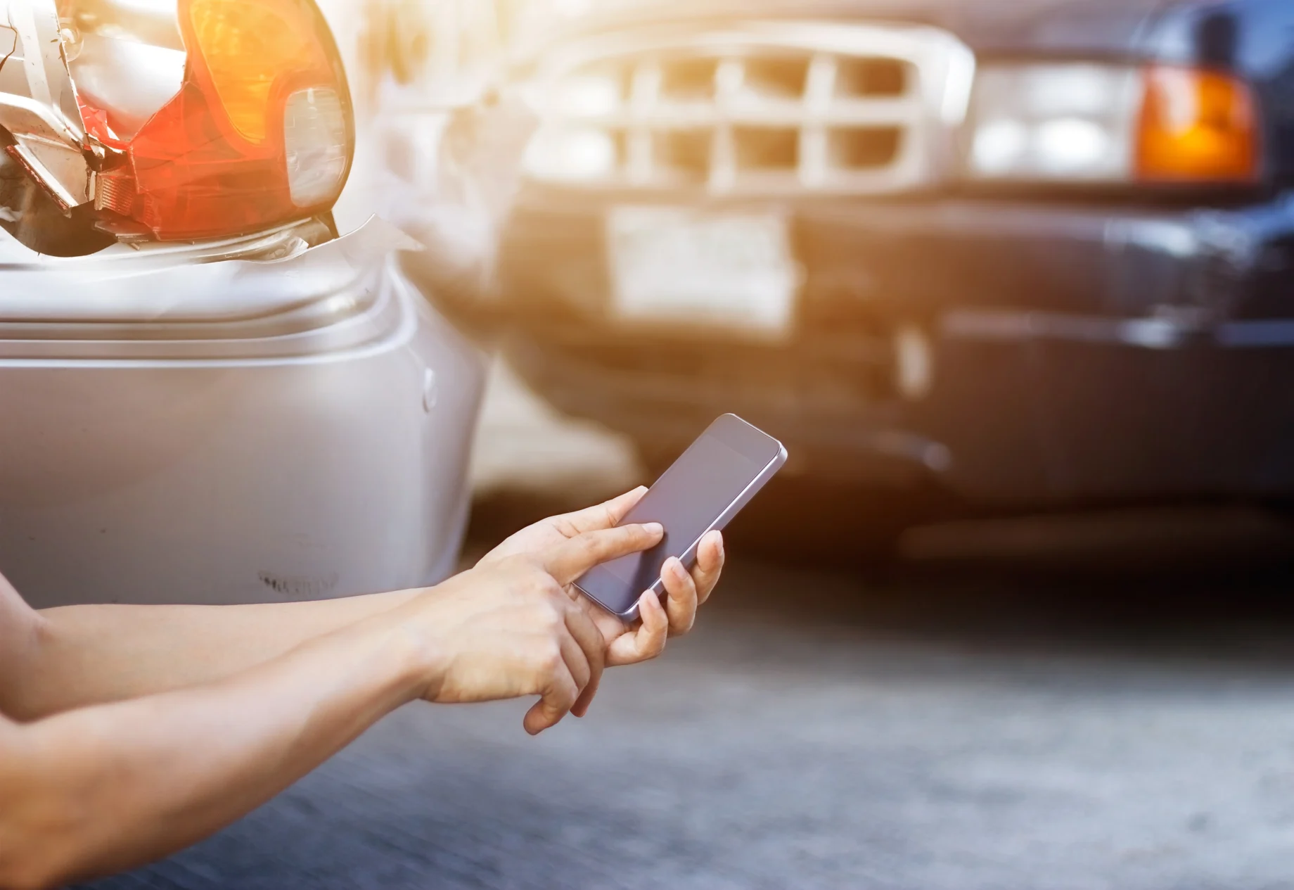 En telefon med et biluheld i baggrunden