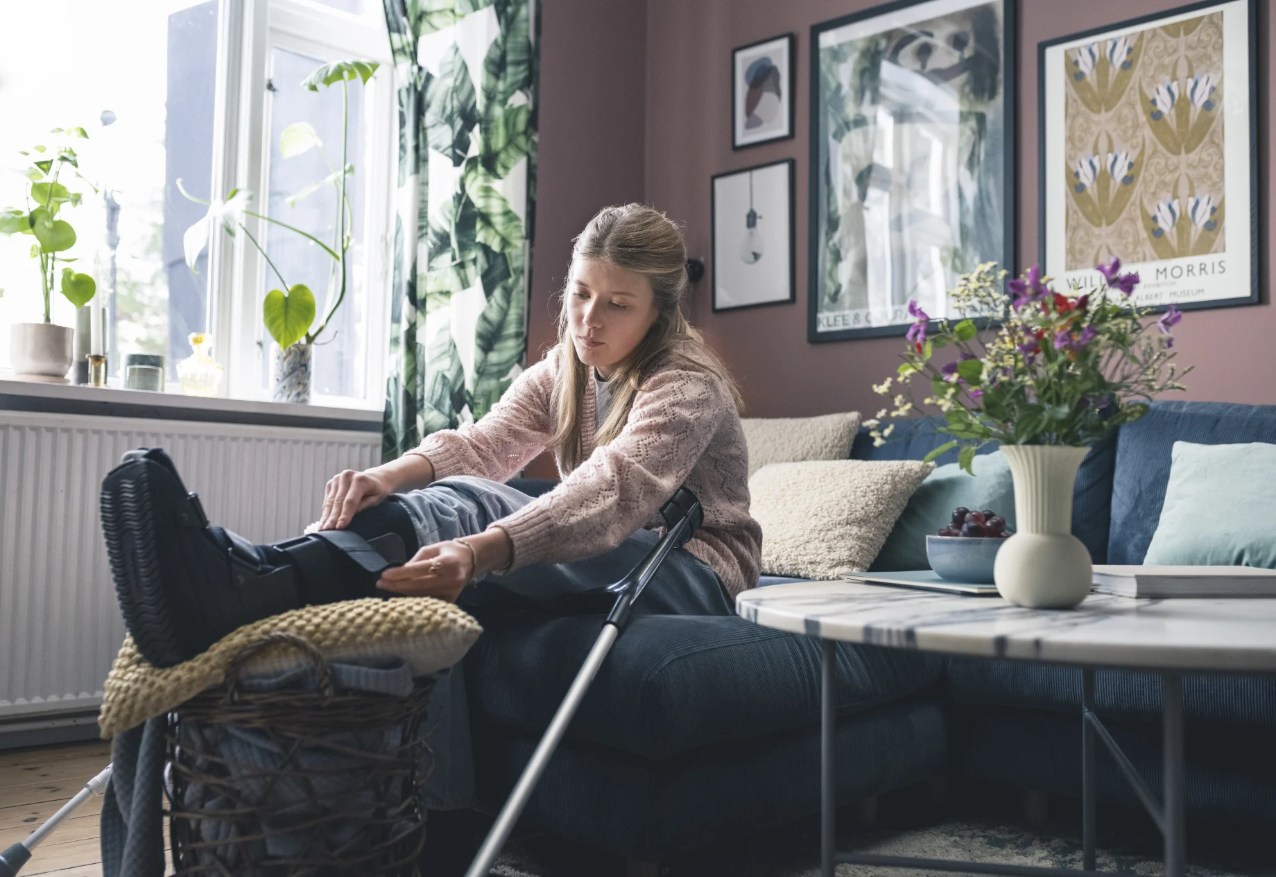 Teenage pige sidder i sofa med krykker og brækket ben