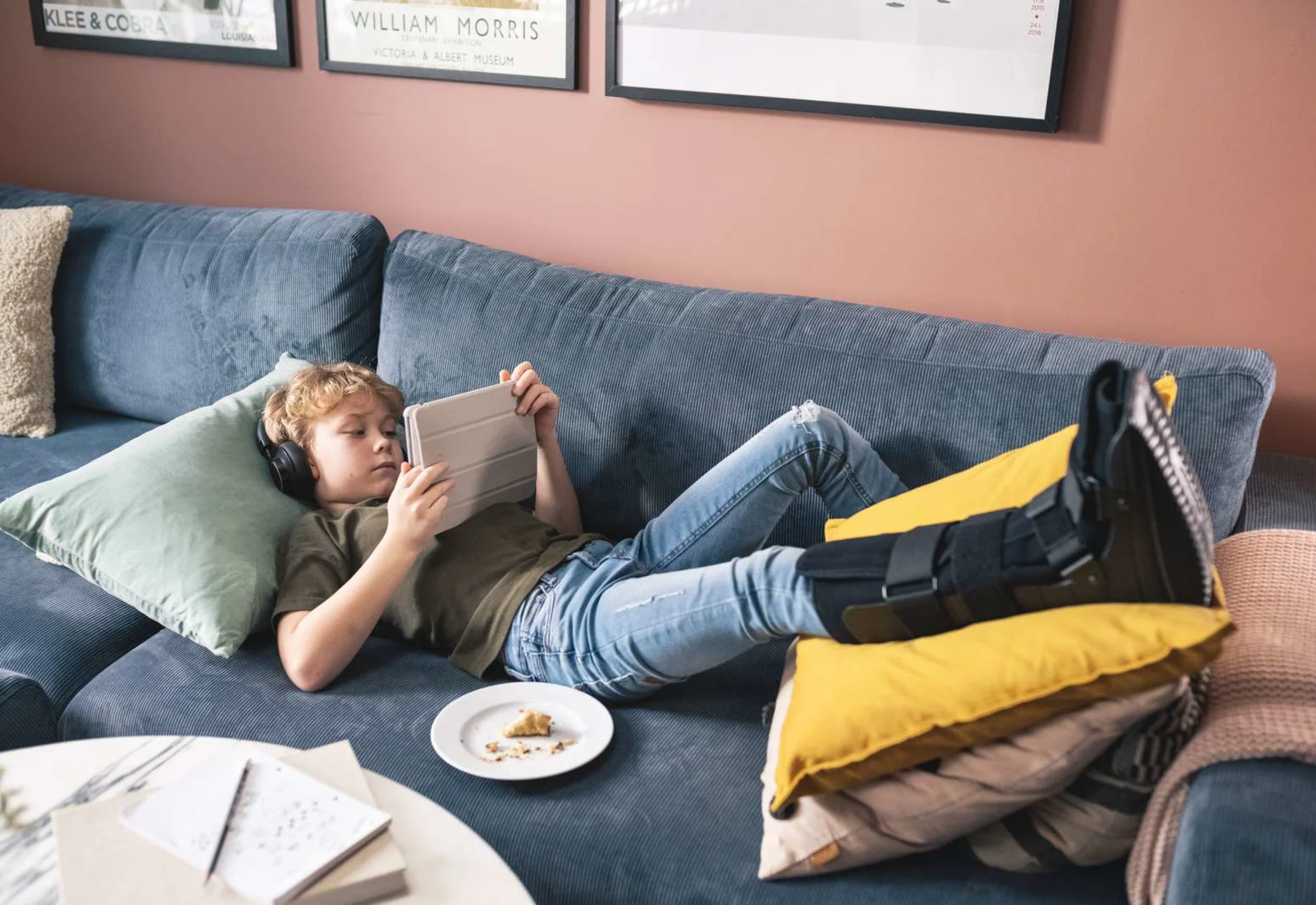 En dreng som ligger på sofaen med sin iPad og et brækket ben
