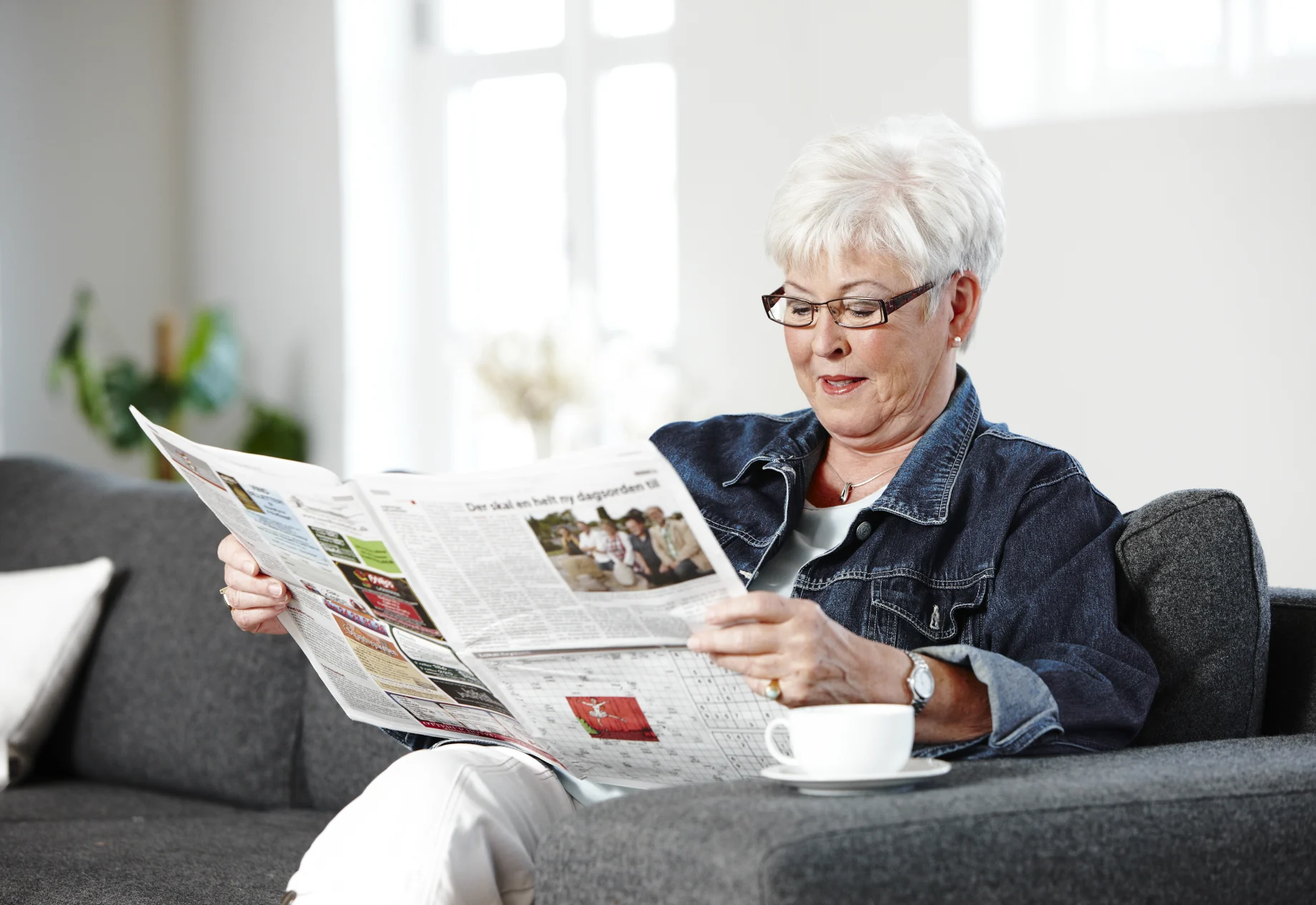 Ældre kvinde som læser i avis
