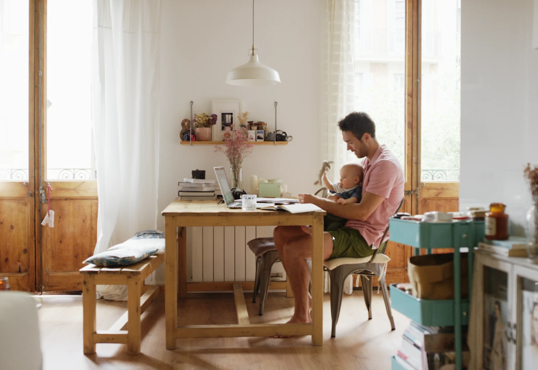 En mand og hans baby som sidder ved spisebord i et hjem