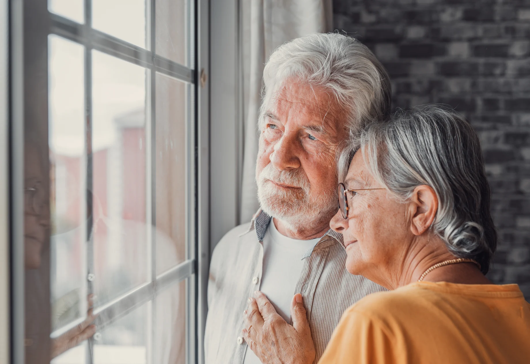 Ældre mennesker som kigger ud af vindue