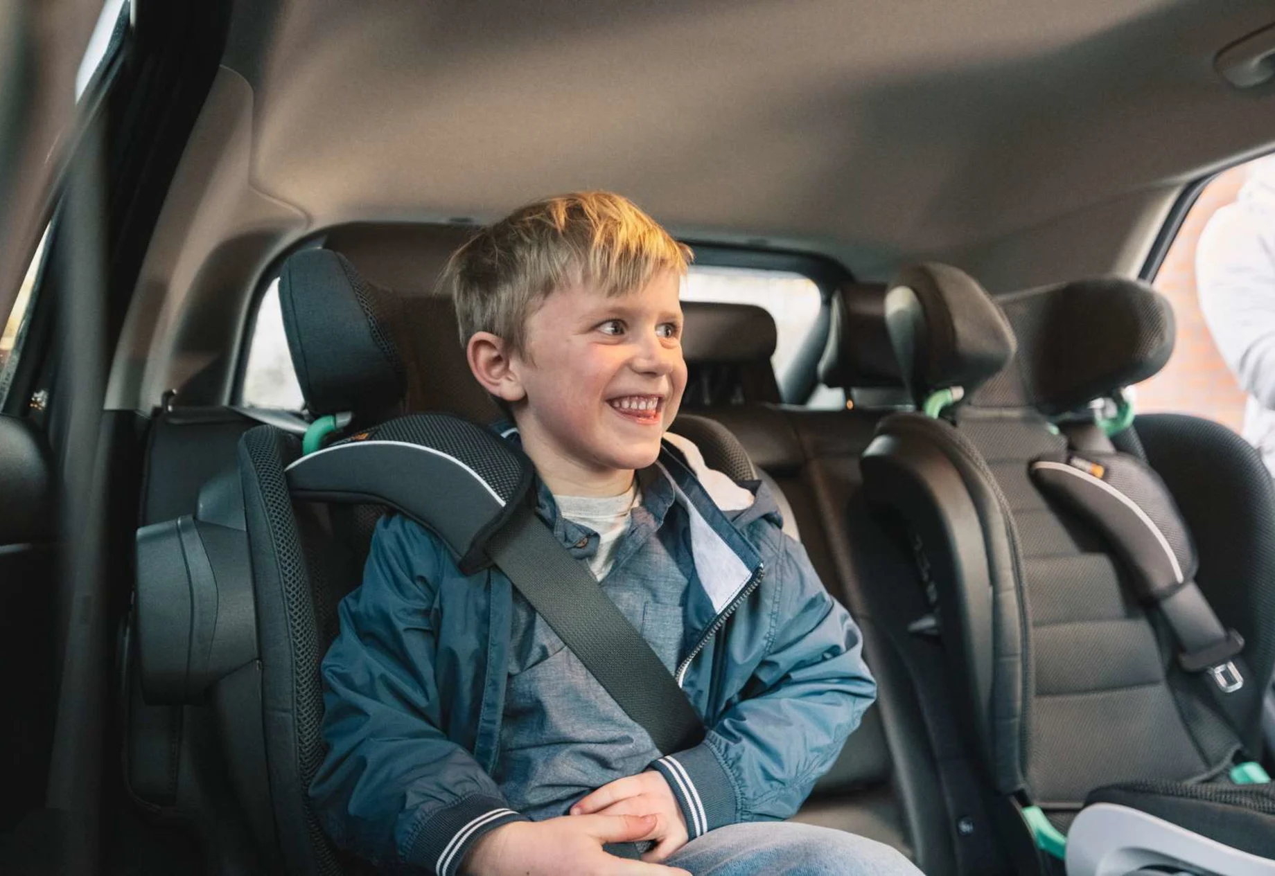 Glad dreng som sidder på bagsædet i en bil