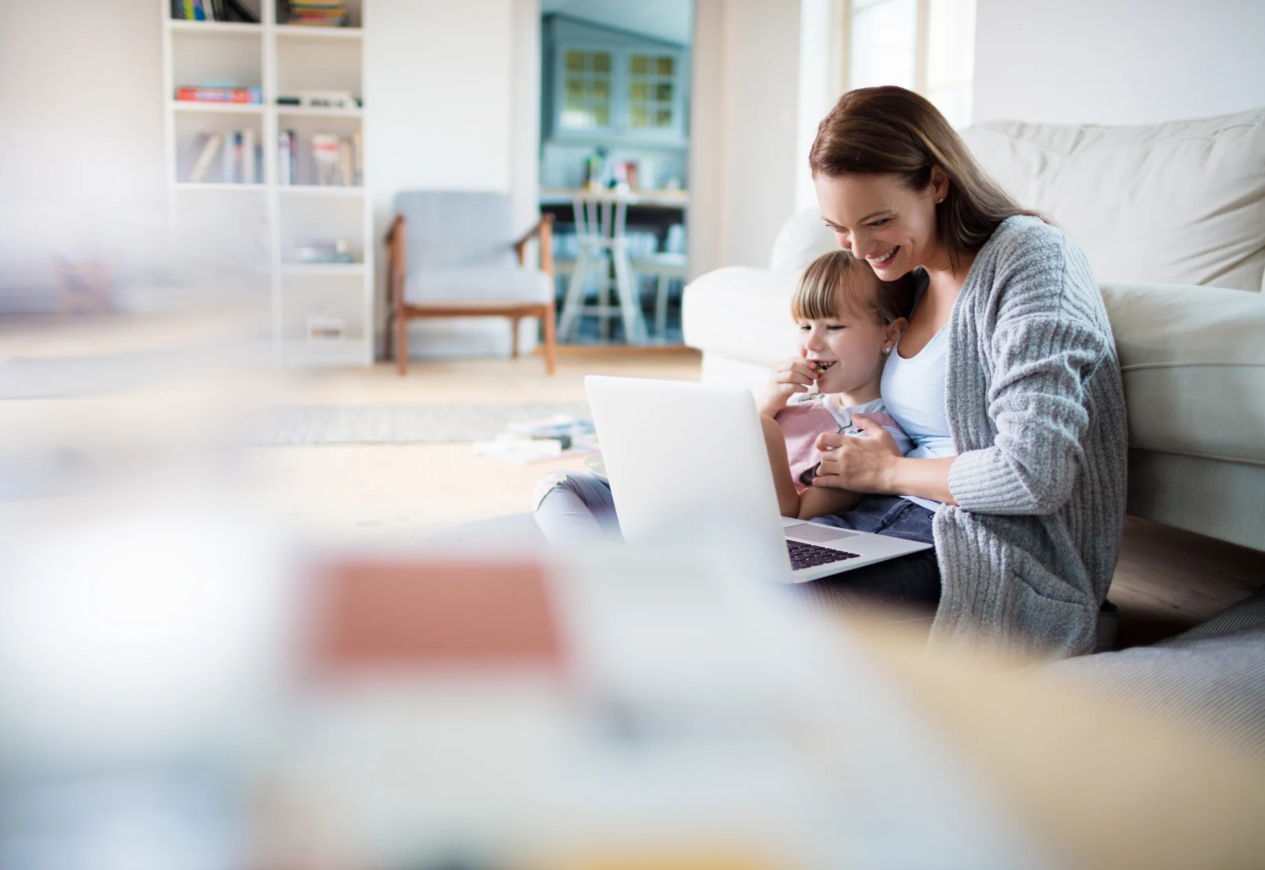 Mor og datter sidder på gulvet i stuen med computer