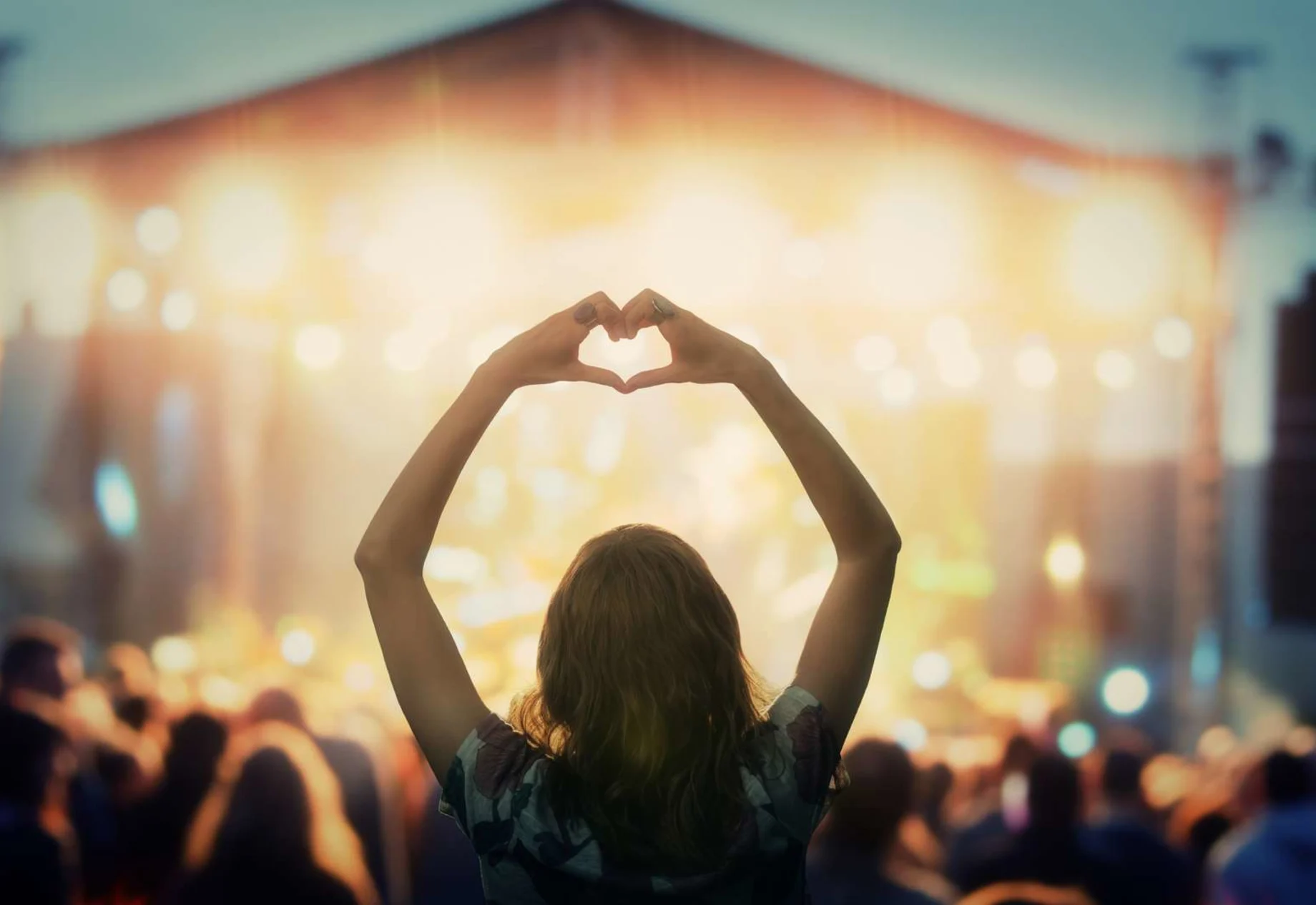 Pige som former et hjerte med sine hænder til en koncert, til en festival