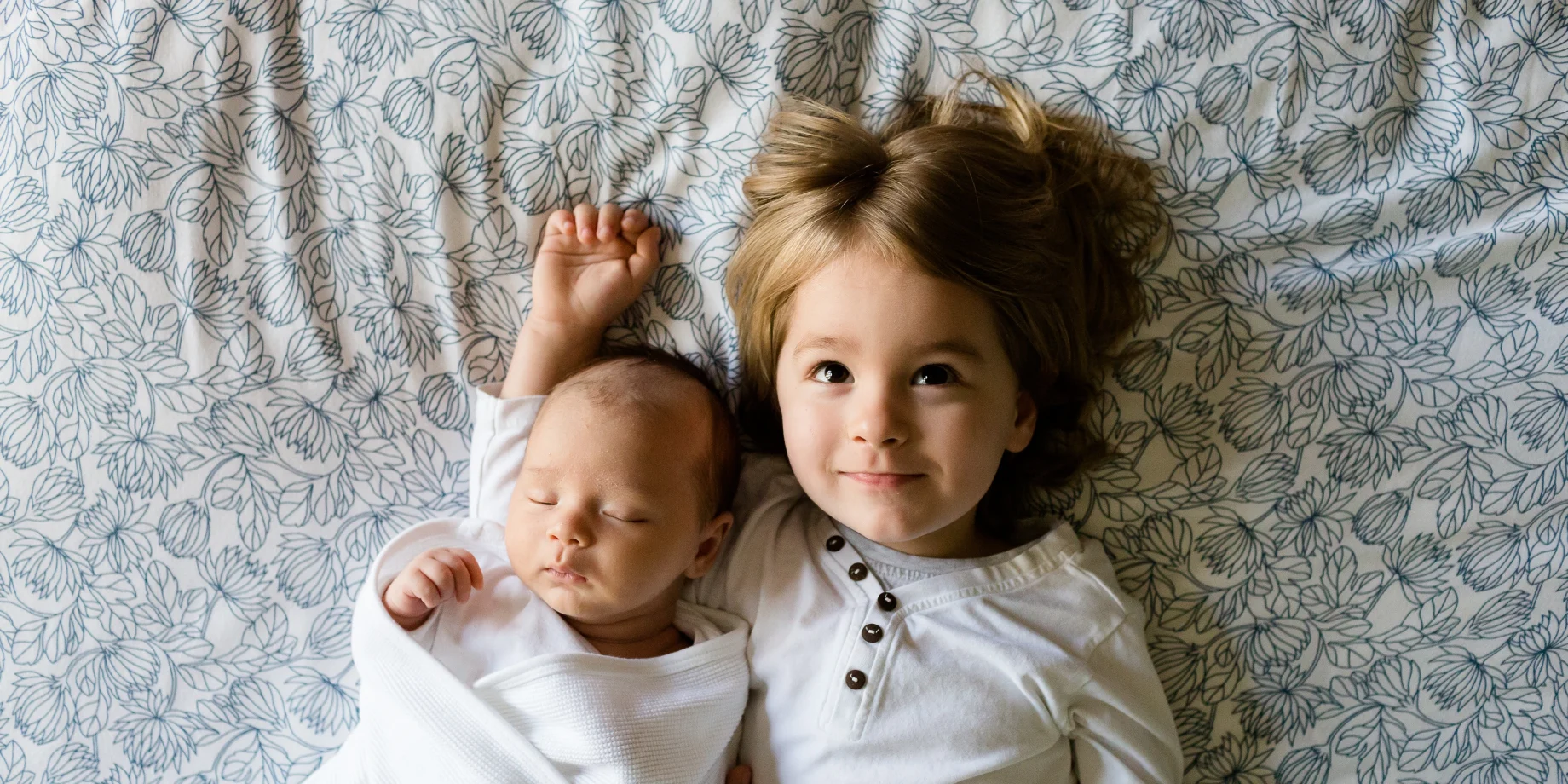 En baby og et barn ligger sammen