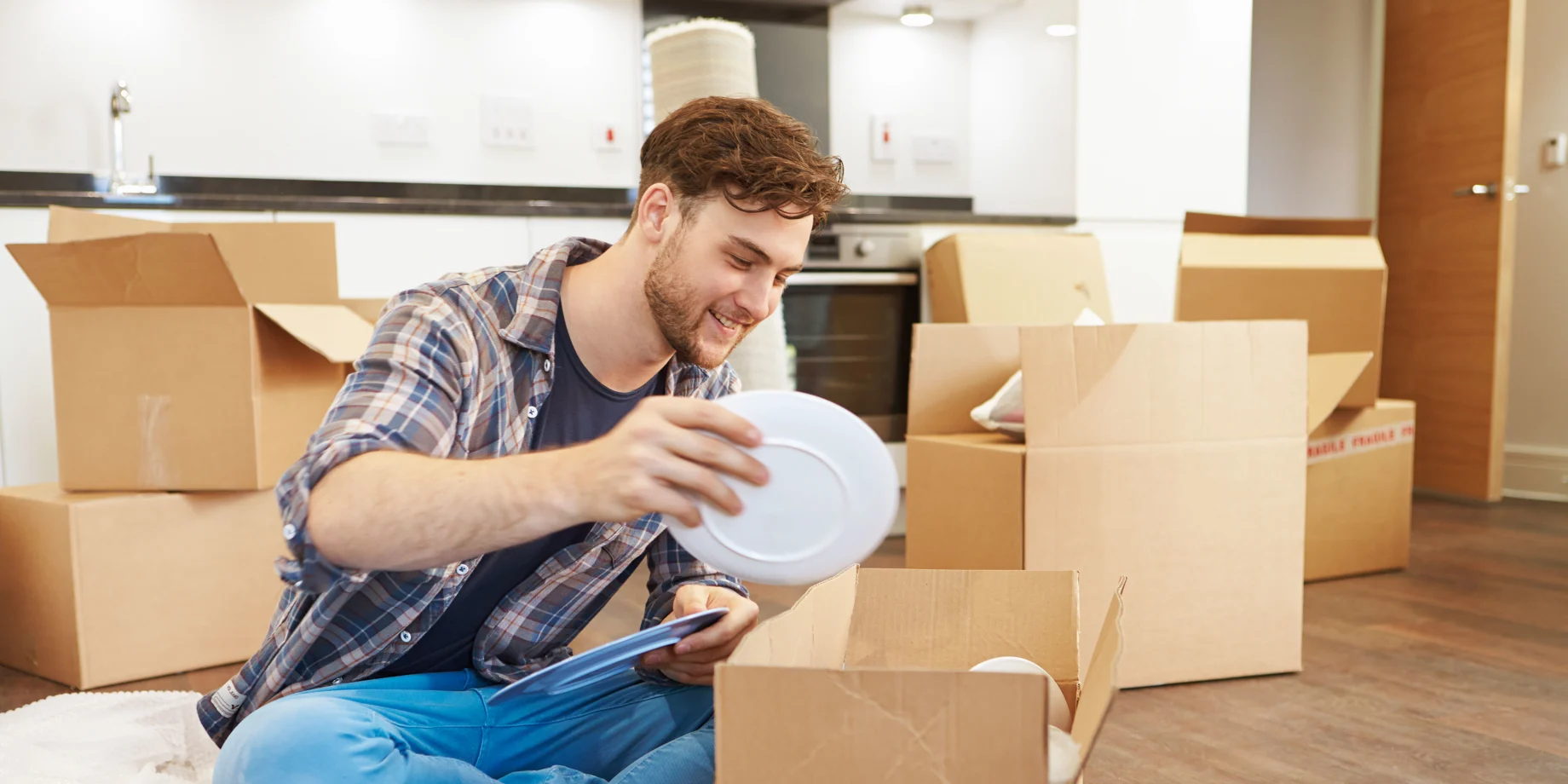 Ung mand pakker ud fra flyttekasser