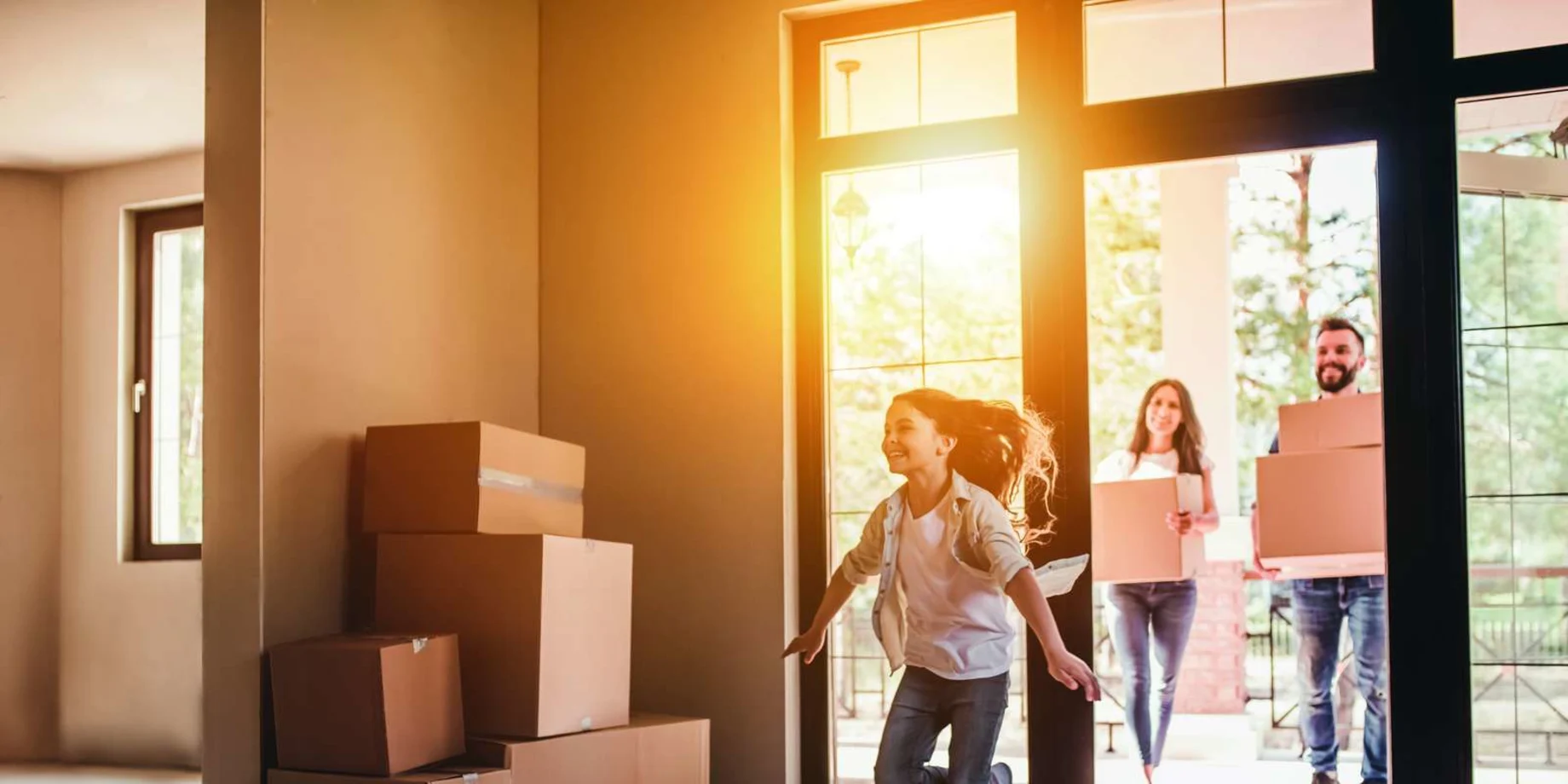 Familie flytter. Hus med flyttekasser og glad pige