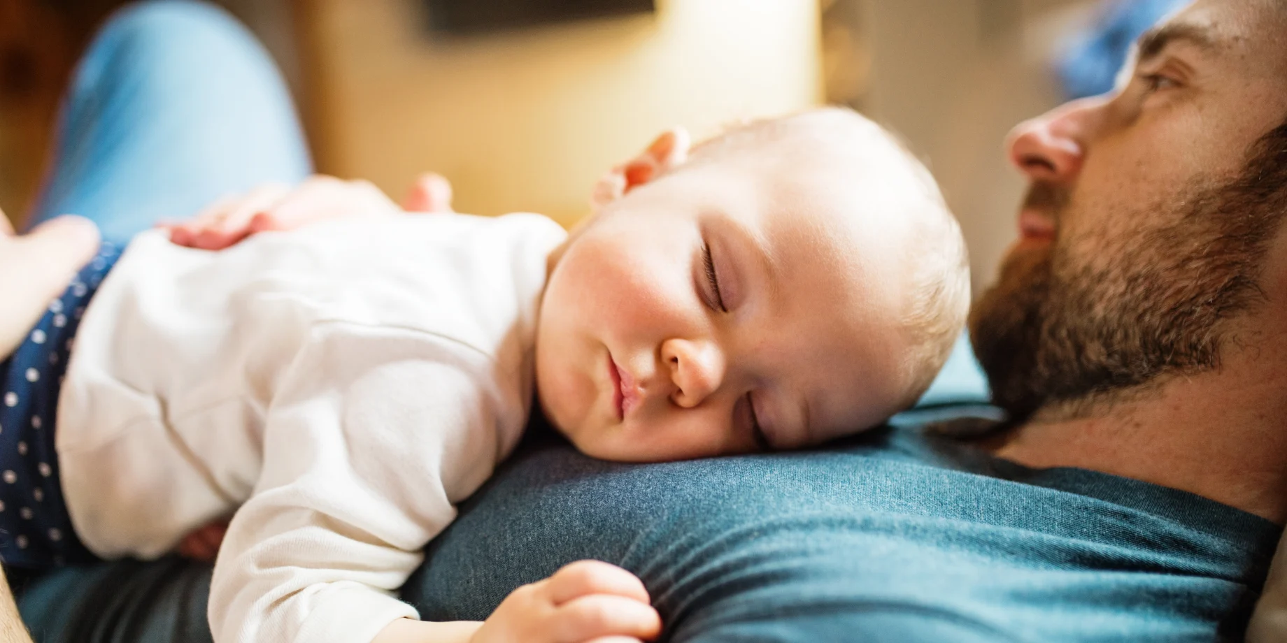 Baby sover i armene på sin far 