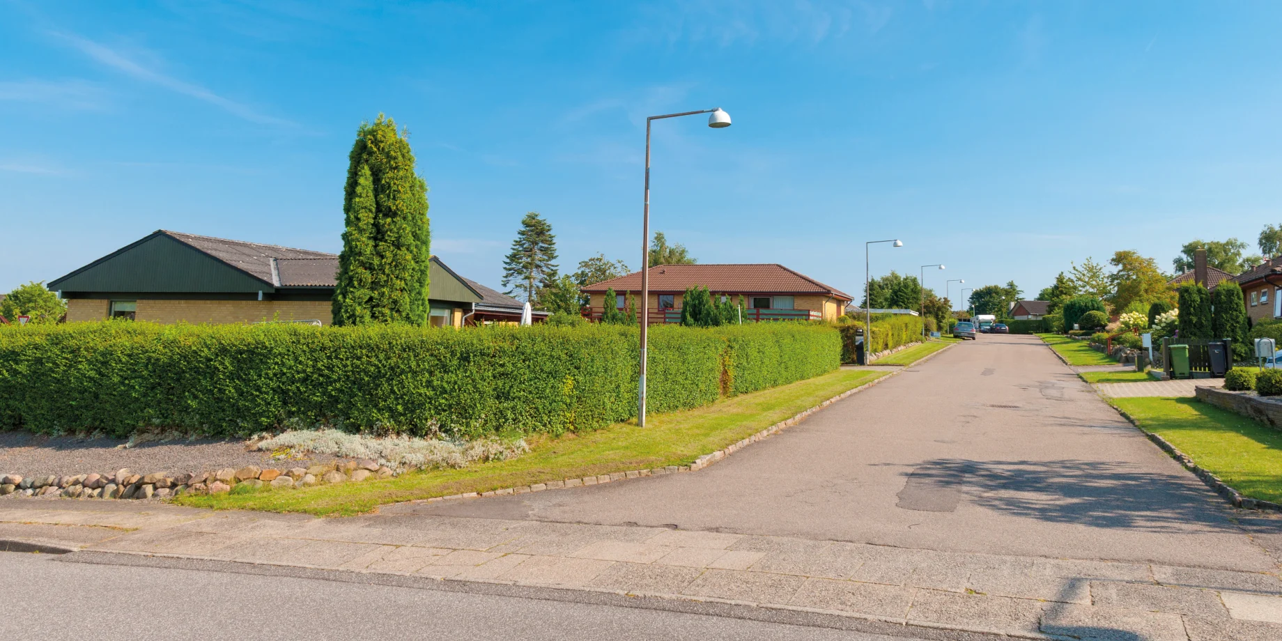 Villavej med huse og blå himmel