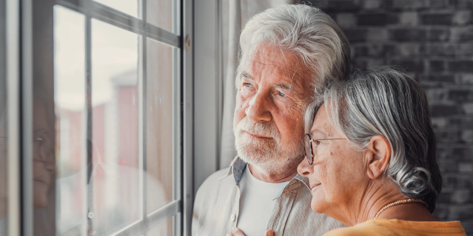 Ægtepar som kigger ud af vinduet