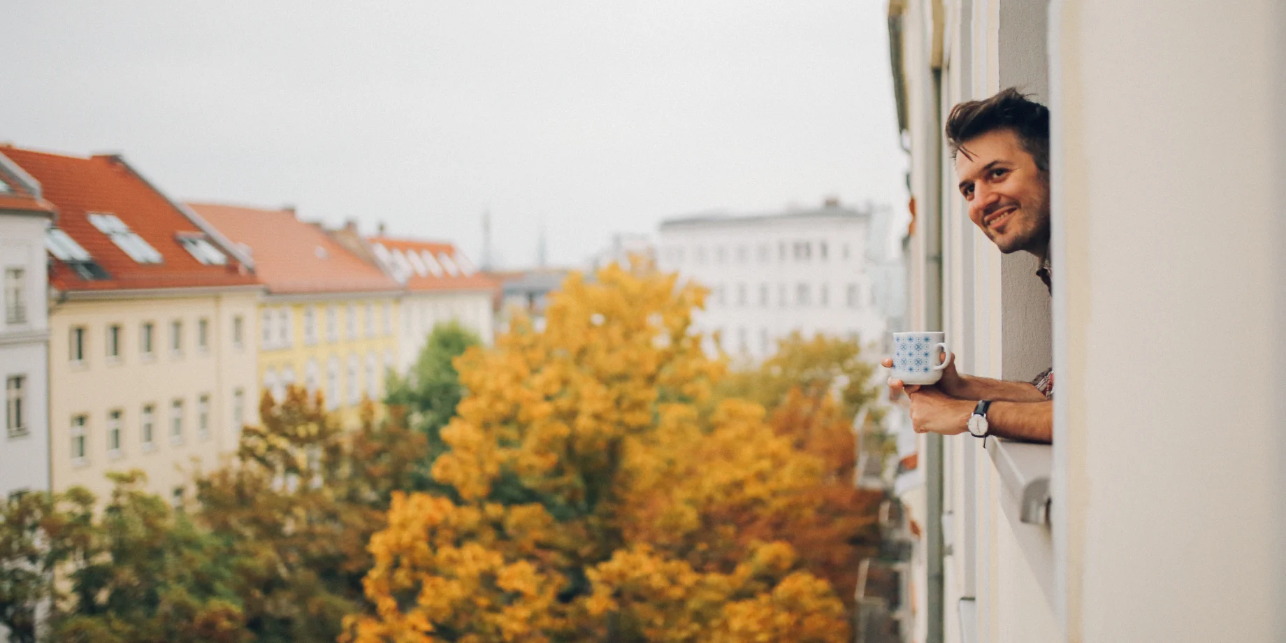 Mand som kigger ud fra sin lejlighed