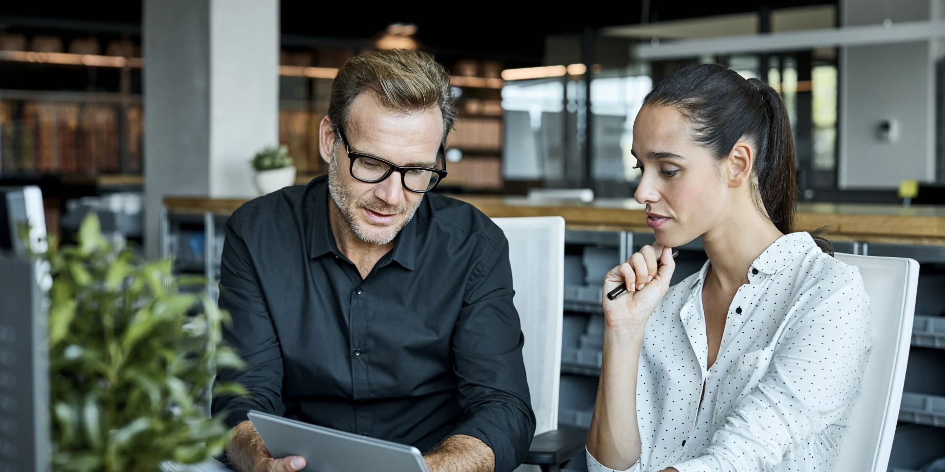 En mand og kvinder sidder på kontor og kigger på en iPad