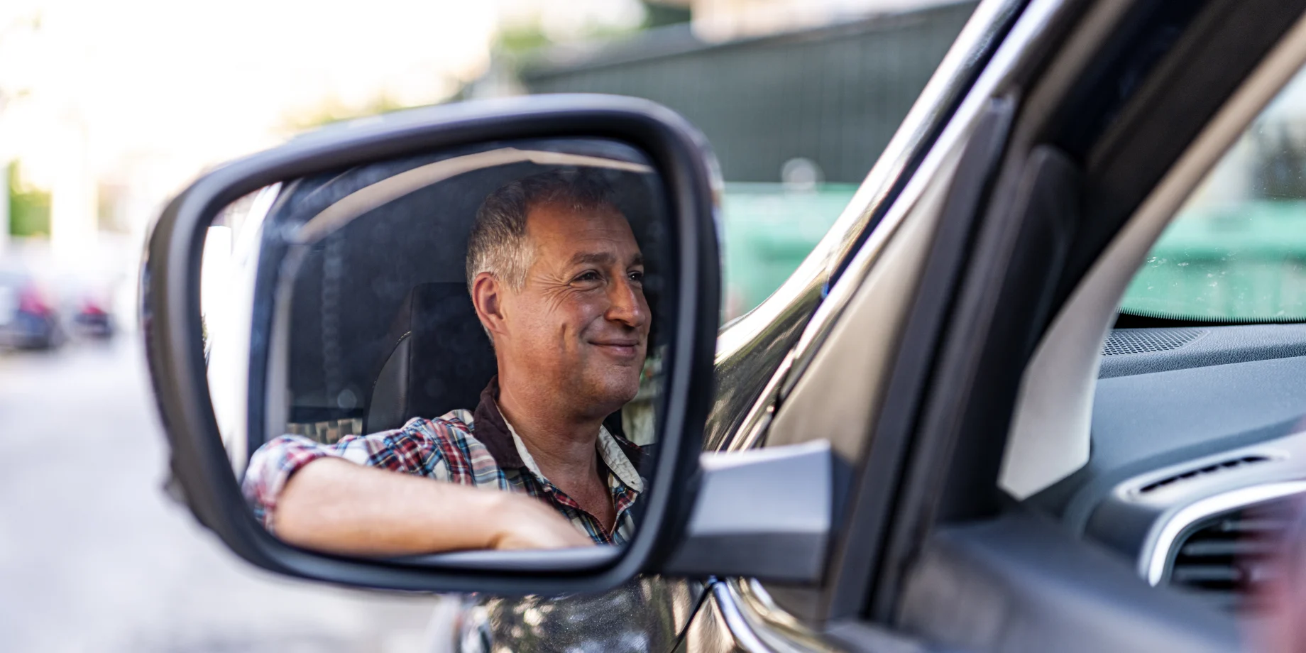 Man ser en mand fra sidespejlet. som sidder inde i bilen