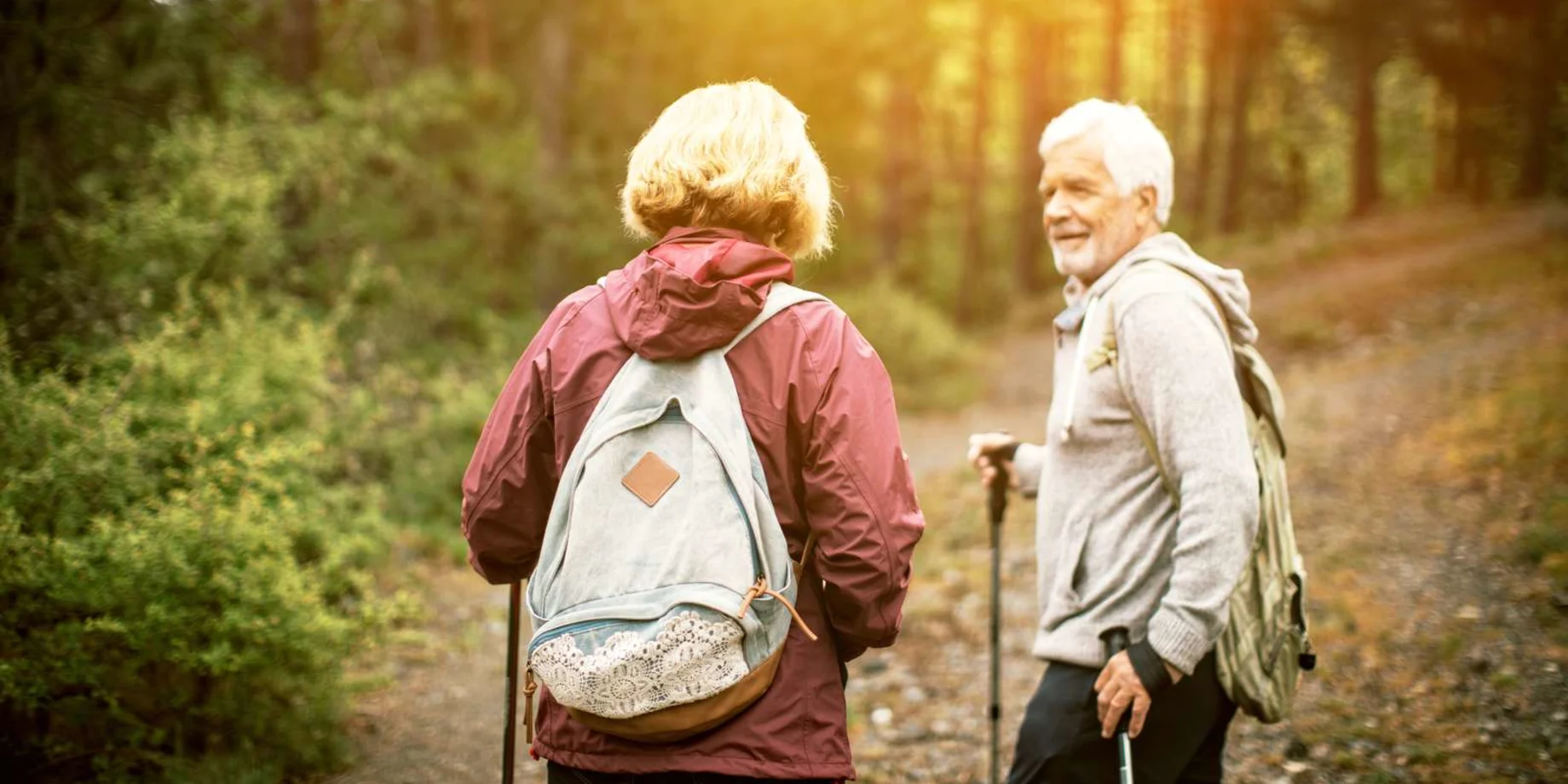 Ældre par som går i tur i en skov