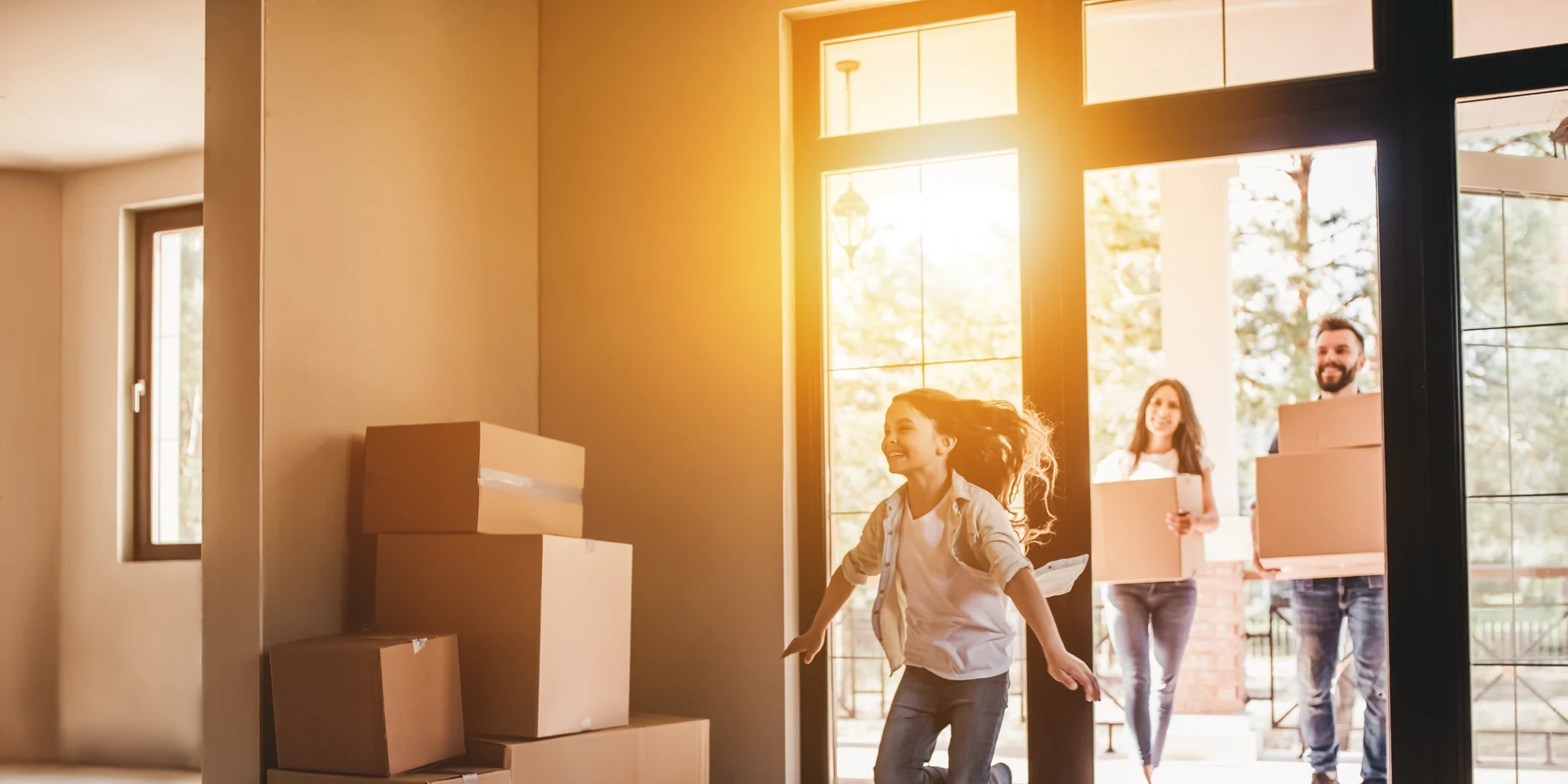 Familie flytter. Hus med flyttekasser og glad pige